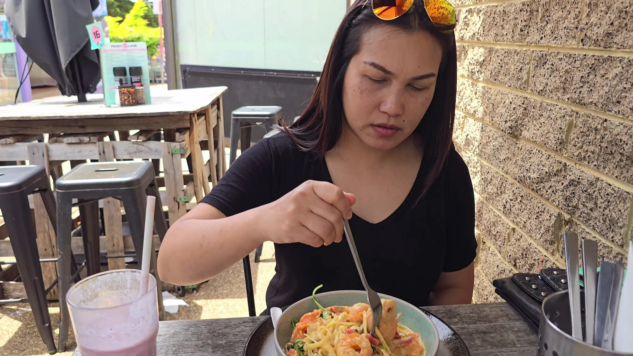 Customer eating noodle dish at outdoor table at Penny Lane Island Cafe