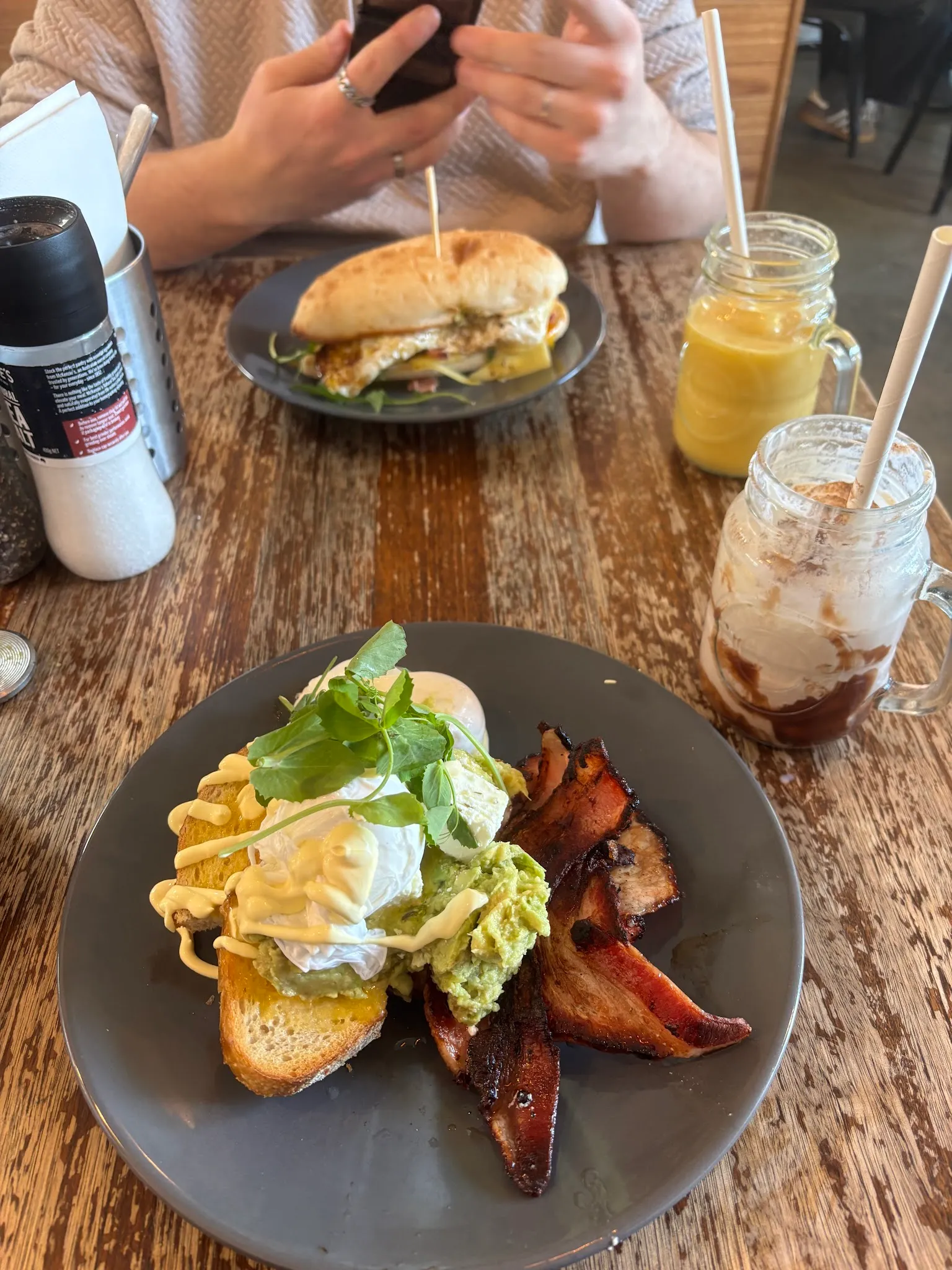 Cafe table with smashed avo on toast, burger, and iced drinks