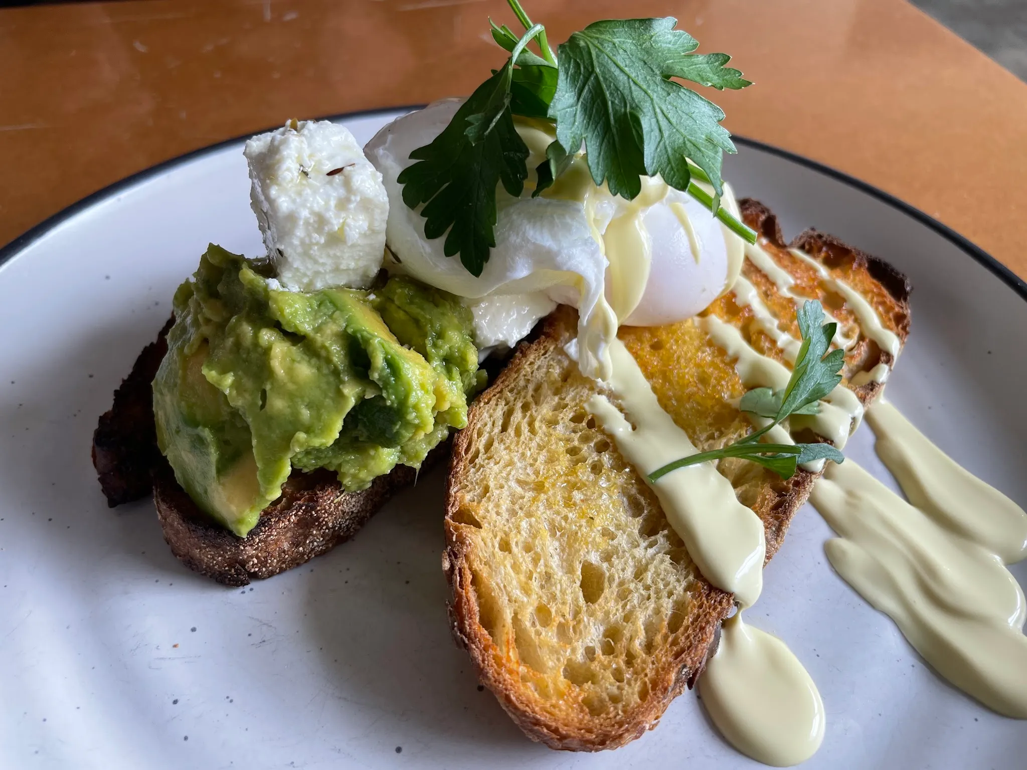 Smashed avocado with poached egg, feta and hollandaise on sourdough toast