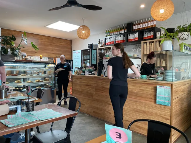 Interior of Penny Lane Island Cafe showing timber bar, staff at work, pendant lights and display cabinet