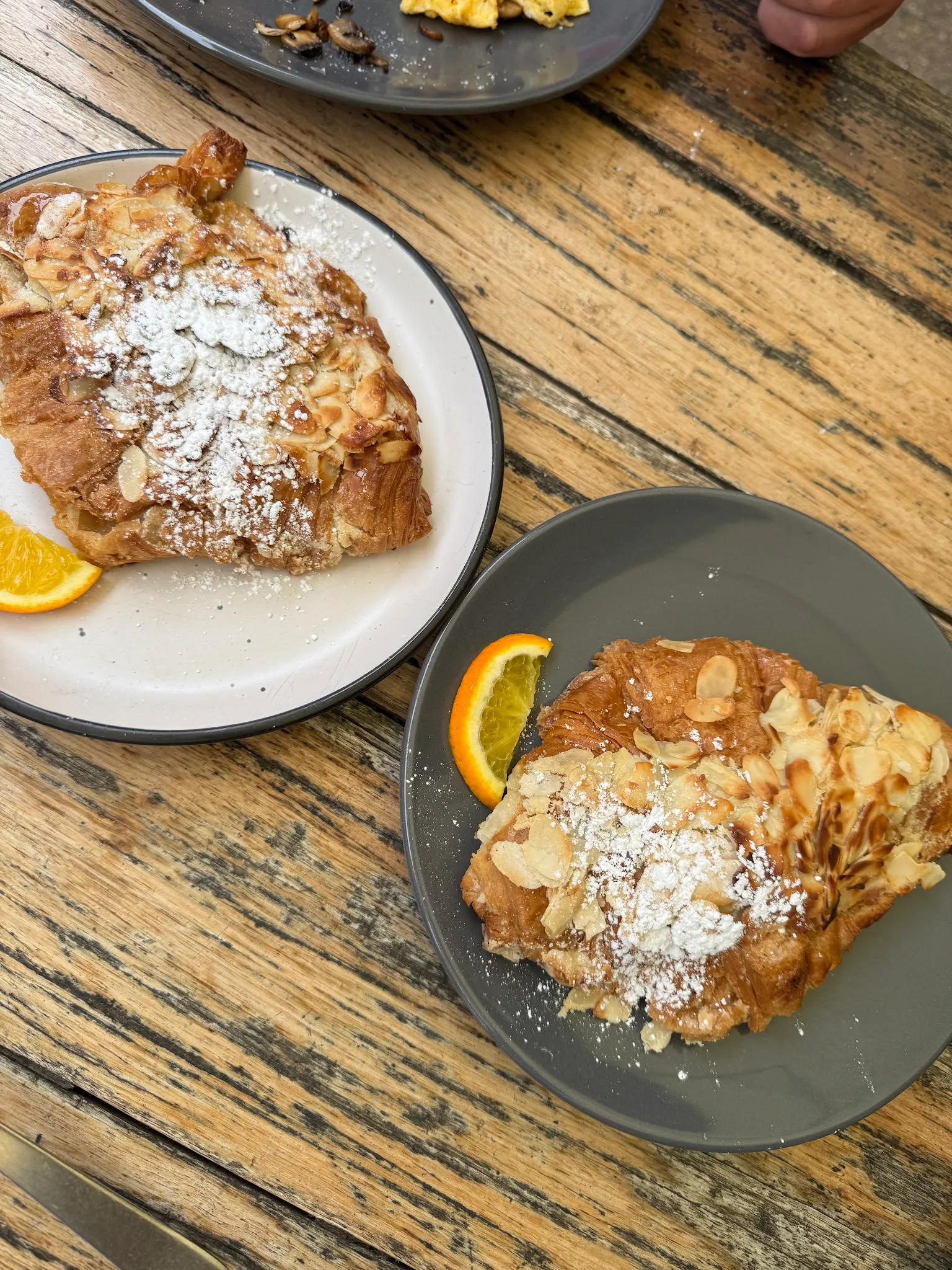 Two almond croissants with icing sugar on plates