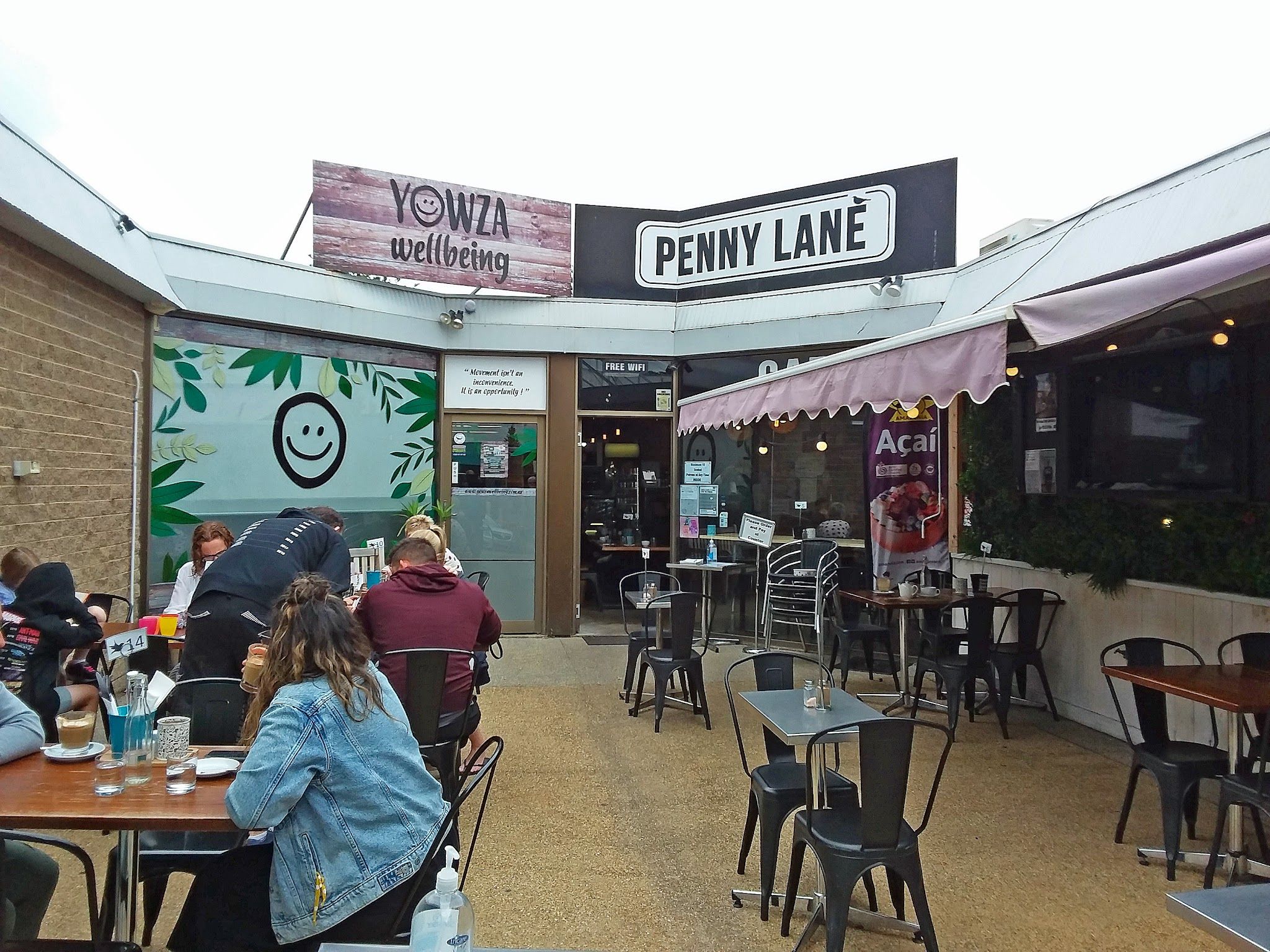 Exterior courtyard of Penny Lane Island Cafe with Penny Lane banner and seated customers