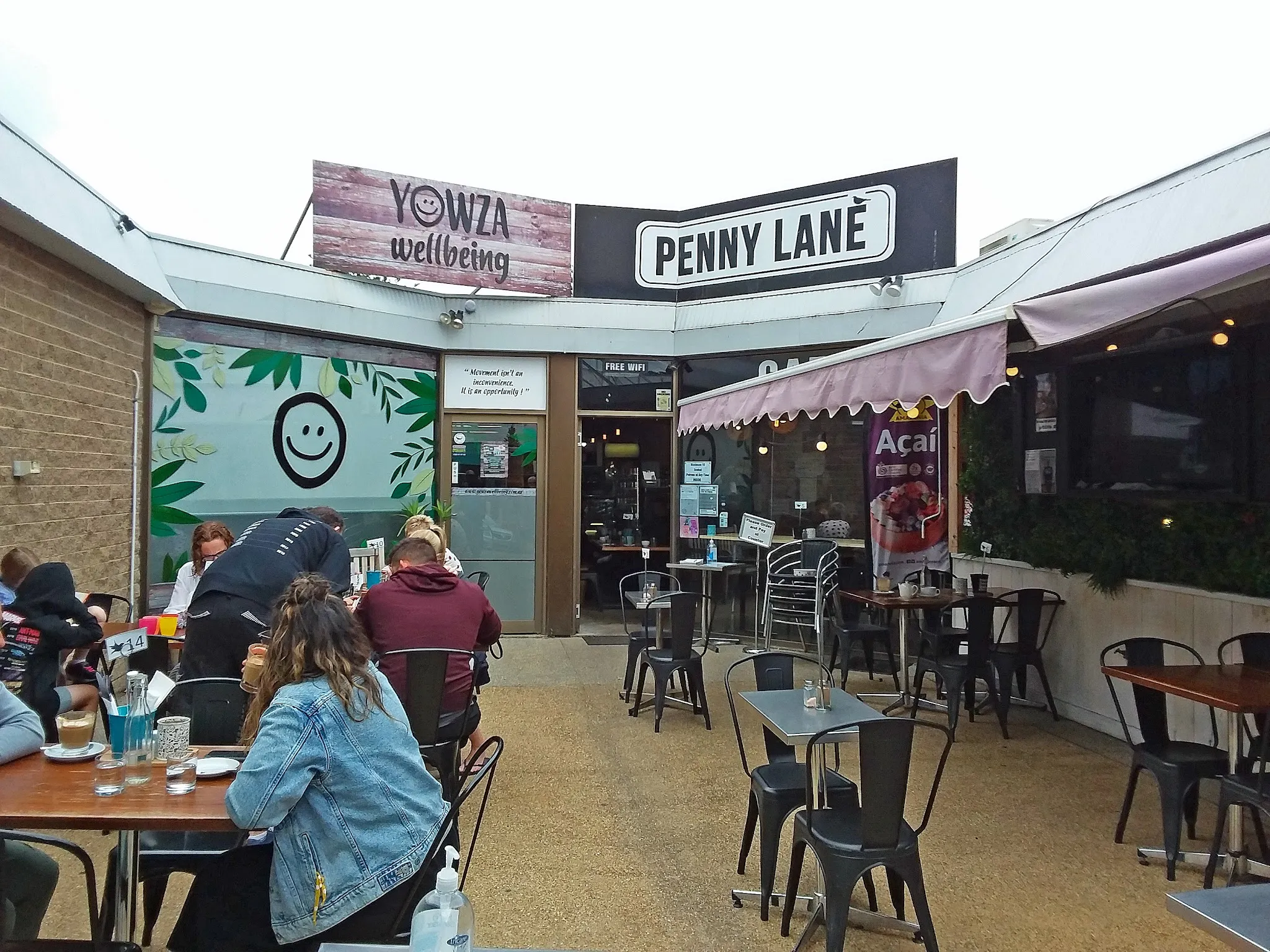 Exterior courtyard of Penny Lane Island Cafe with Penny Lane banner and seated customers